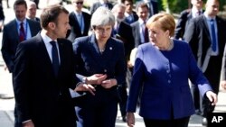 FILE - German Chancellor Angela Merkel, right, speaks with French President Emmanuel Macron, left, and British Prime Minister Theresa May after meeting on the sidelines of an EU-Western Balkans summit in Sofia, Bulgaria, May 17, 2018.