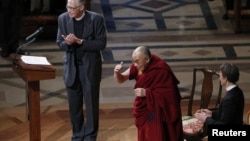 The Dalai Lama (C) greets the audience before his speech at the National Cathedral in Washington, March 7, 2014. Also pictured are the Very Reverend Gary Hall (L) and the Reverend Mariann Edgar Budde (R).
