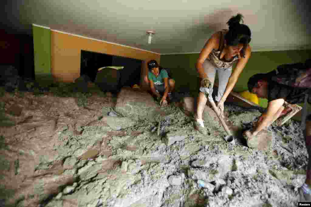 People remove mud and rocks from their house after a massive landslide in Chosica, March 24, 2015. Seven people were killed and more were feared dead in Peru after a massive landslide buried parts of a town amid heavy rains, authorities said.