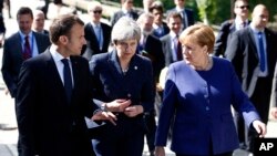 German Chancellor Angela Merkel, right, speaks with French President Emmanuel Macron, left, and British Prime Minister Theresa May after meeting at a hotel on the sidelines of an EU-Western Balkans summit in Sofia, Bulgaria, May 17, 2018. 