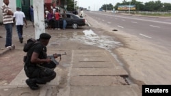 A Congolese security officer takes position to secure the street near the state television headquarters in the capital Kinshasa, Dec.30, 2013.