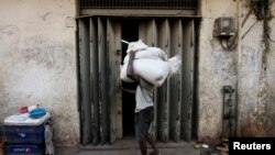 FILE - A laborer tries to open a door at a store room as he carries sacks of rice near a main market in Colombo, Sri Lanka, Feb. 21, 2017. 