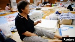 An evacuee uses a paper fan as she rests at Okada elementary school that is used as an evacuation center in Mabi town in Kurashiki, Okayama Prefecture, Japan, July 12, 2018.