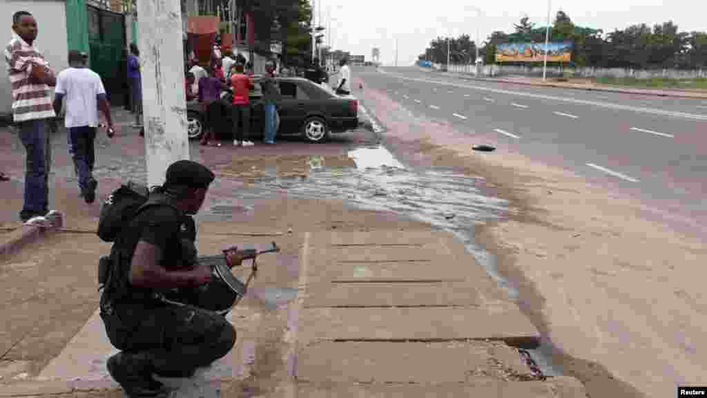 Un agent des forces de l&#39;ordre prend position, arme à la main et prête à être utilisée, lors d&#39;une émeute à Kinshasa prêt de la télévision nationale congolaise, le 30 décembre 2013. REUTERS/Jean Robert N&#39;Kengo. 