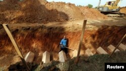 A man walks in a mass grave amongst coffins of unidentified remains of Rohingya people found at a traffickers camp in Wang Kelian last month, at a cemetery near Alor Setar, Malaysia, June 22, 2015.