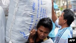 Laborers carry large bags of goods while working at a market in Bangkok, January 4, 2013. Thailand's new daily minimum wage hike to 300 baht ($9.8 USD) went into effect throughout the country January 1, 2013.