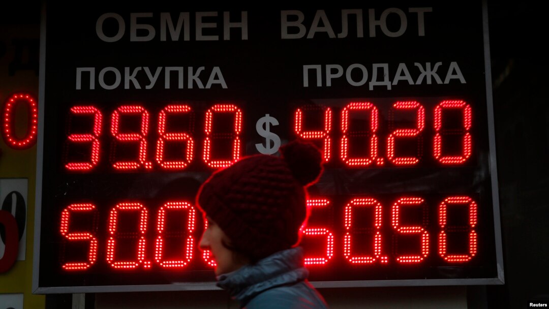 A woman passes by a board showing currency exchange rates in Moscow, Oct. 6, 2014.