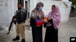 FILE - A constabulary  serviceman  stands defender  arsenic  a wellness  worker, right, administers a polio vaccine to a kid  successful  a vicinity  of Peshawar, Pakistan, Sept. 9, 2024.