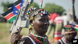 FILE - A South Sudanese woman wears the national flag and carries a mock gun as she attends an independence day ceremony in the capital Juba, July 9, 2015. 