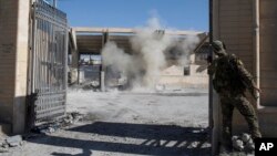 FILE - A member of the U.S.-backed Syrian Democratic Forces SDF throws a bomb to check for more explosives as he helps clear the stadium that was the site of Islamic State fighters' last stand in the city of Raqqa, Syria, Oct. 18, 2017. 