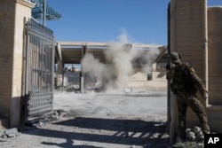 FILE - A member of the U.S.-backed Syrian Democratic Forces throws a bomb to check for more explosives as they clear the stadium that was the site of Islamic State fighters' last stand in the city of Raqqa, Syria, Oct. 18, 2017.