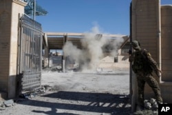 FILE - A member of the U.S.-backed Syrian Democratic Forces SDF throws a bomb to check for more explosives as they clear the syadium that was the site of Islamic State fighters' last stand in the city of Raqqa, Syria, Oct. 18, 2017.