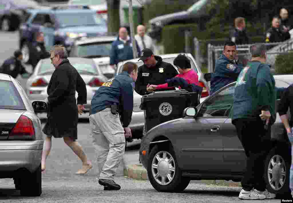 19일 보스턴 테러 용의자 추적을 위해 경찰들이 미국 메사추세츠 주 워터타운 곳곳을 수색하고 있는 가운데, 워터타운 주민들이 급하게 집 안에서 뛰쳐나오고 있다.