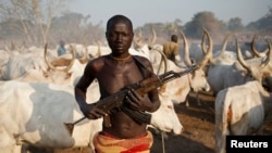 A man from Dinka tribe holds his rifle in front of cows in a Dinka cattle herders camp in central South Sudan, December 14, 2013. (REUTERS/Goran Tomasevic)