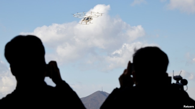 People take pictures of the "Volocopter 2X" drone taxi during an Urban Air Mobility Airport Demo event at Gimpo Airport in Seoul, South Korea, November 11, 2021. (REUTERS/Heo Ran)