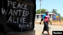 A woman walks past a message of peace in Kibera slum in the capital Nairobi, February 28, 2013.