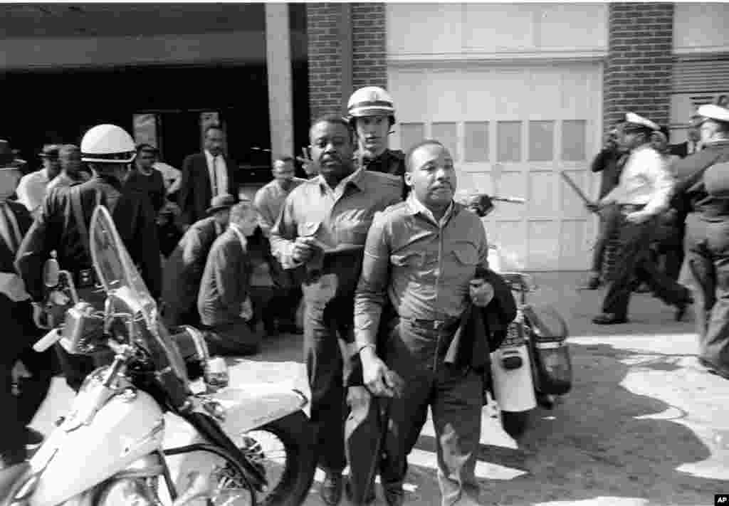 Rev. Ralph Abernathy and Martin Luther King, Jr., are taken by a policeman as they led a line of demonstrators into the business section of Birmingham, Alabama, April 12, 1963. 