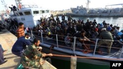 海上获救的非洲国家移民和难民抵达利比亚的黎波里的一个军事基地