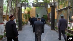 Uyghurs and other members of the faithful walk under an arch with security cameras as they leave after prayers at the Id Kah Mosque in Kashgar in western China's Xinjiang Uyghur Autonomous Region, April 19, 2021.