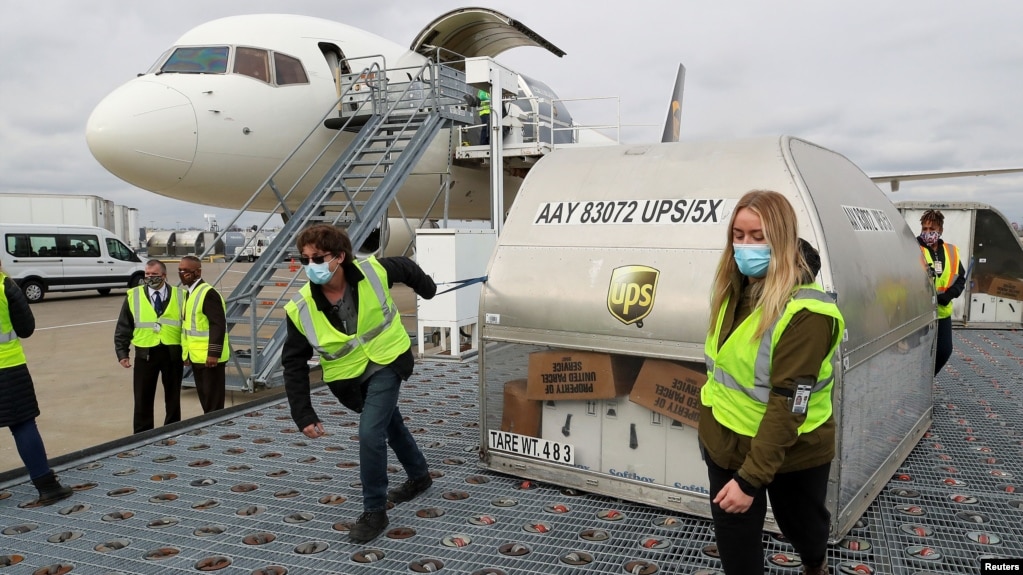 2020年12月13日UPS员工在肯塔基州路易斯维尔穆罕默德·阿里国际机场移动装载辉瑞疫苗的集装箱。(photo:VOA)