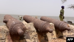 Un policier passe devant des canons sur l'île de Kunta Kinteh, anciennement connue sous le nom de James Island, une île de la Gambie, à 30 km de l'embouchure de la rivière et près de Juffureh, le 8 avril 2017.