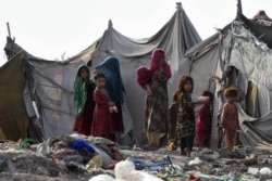 FILE - Children of Afghan refugees play outside tents in Afghan Basti area on the outskirts of Lahore on June 19, 2021 on the eve of World Refugee Day.