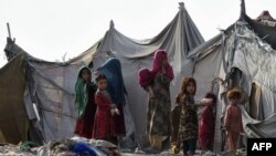 FILE - Children of Afghan refugees play outside tents in Afghan Basti area on the outskirts of Lahore on June 19, 2021 on the eve of World Refugee Day.