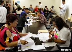 FILE - People fill out paperwork for the Deferred Action for Childhood Arrivals program at the Coalition for Humane Immigrant Rights of Los Angeles in Los Angeles, California, August 15, 2012.