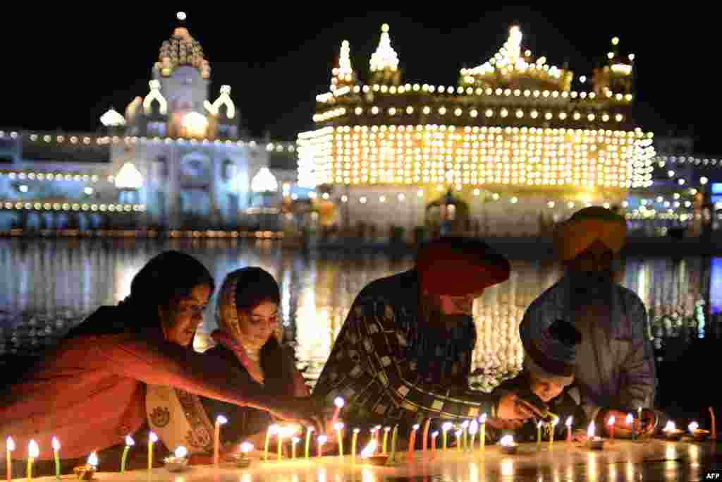 Một tín đồ Sikh Aán Độ ngoan đạo thắp nến tại Đền Vàng ở Amritsar. Người Sikh kỷ niệm 348 năm ngày sanh của Giáo chủ đạo Sikh đời thứ 10 Gobind Singh. 