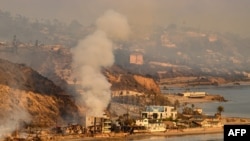 FILE - In this aerial view taken from a helicopter, homes burn on Pacific Coast Highway during the Palisades fire in Malibu, California, on January 9, 2025.