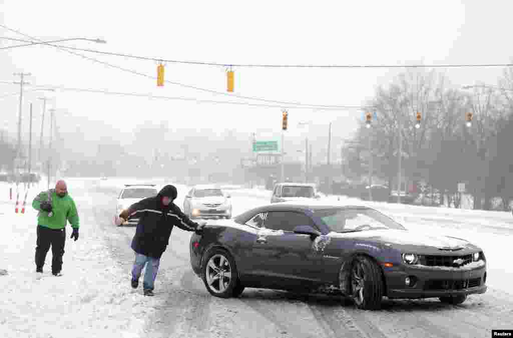 Tom Bladel works to push a stranded motorist back onto the road in Pineville, North Carolina, Feb. 12, 2014. 