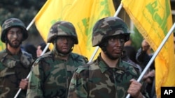 FILE - Hezbollah fighters hold their group's flags at a rally in Nabatiyeh, southern Lebanon, Nov. 7, 2014.