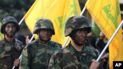 Pejuang Hizbullah memegang bendera mereka saat parade di Nabatiyeh, Lebanon selatan, 7 November 2014 (Foto: dok).