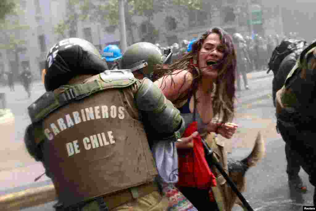 A demonstrator is detained by riot police during a rally against Columbus Day in downtown Santiago, Chile, Oct. 9, 2017.