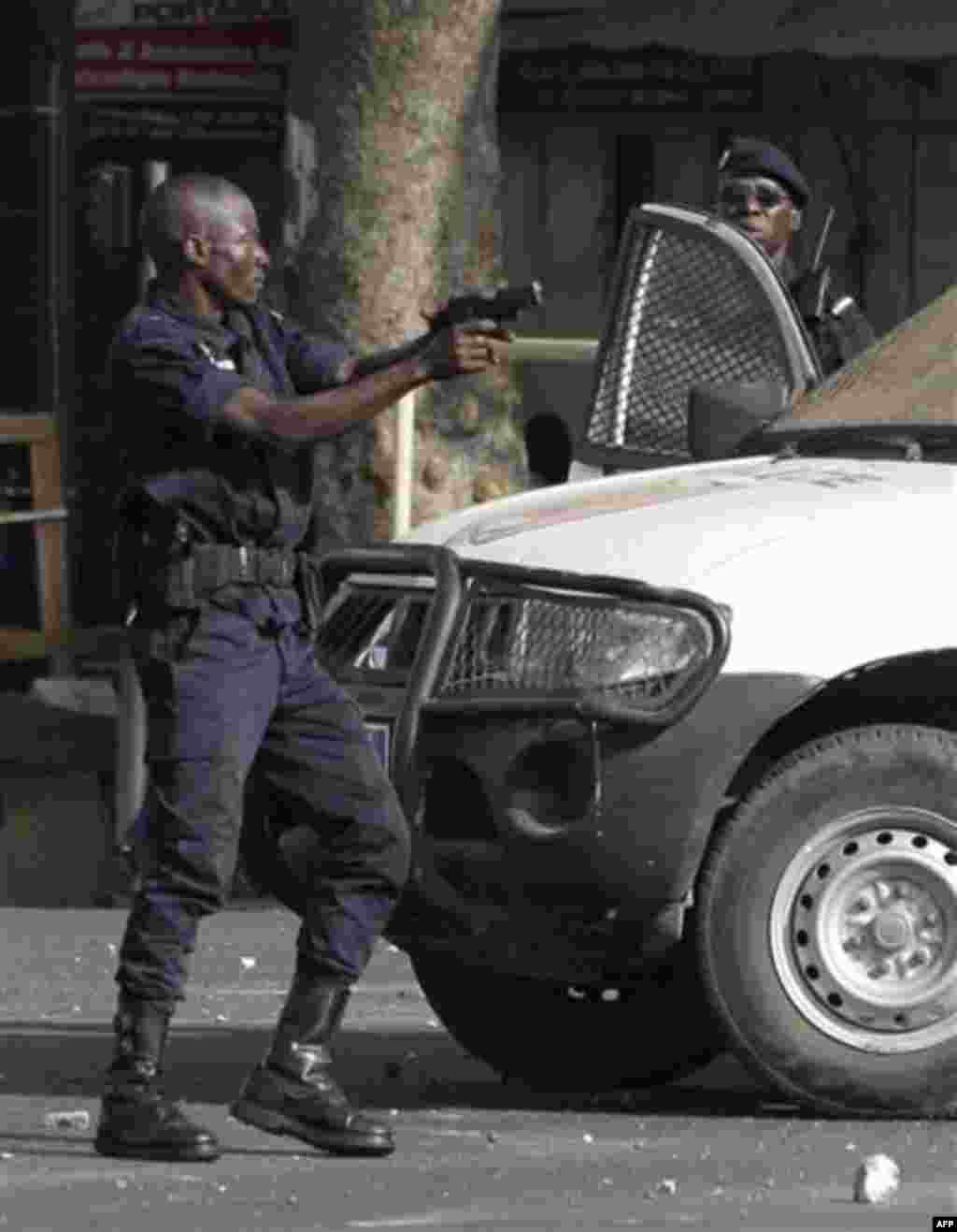 A policeman reacts by firing live rounds from a pistol, after being struck in the head with a rock by anti-government protesters, during running clashes in central Dakar, Senegal Friday, Feb. 17, 2012. Anti-government protesters and police clashed for a t