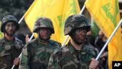 FILE - Hezbollah fighters hold their group's flags at a rally in Nabatiyeh, southern Lebanon, Nov. 7, 2014. The Gulf Cooperation Council announced Wednesday it has labeled the Lebanese militant group a terrorist organization.