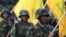 FILE - Hezbollah fighters hold their group's flags at a rally in Nabatiyeh, southern Lebanon, Nov. 7, 2014. The Gulf Cooperation Council announced Wednesday it has labeled the Lebanese militant group a terrorist organization.