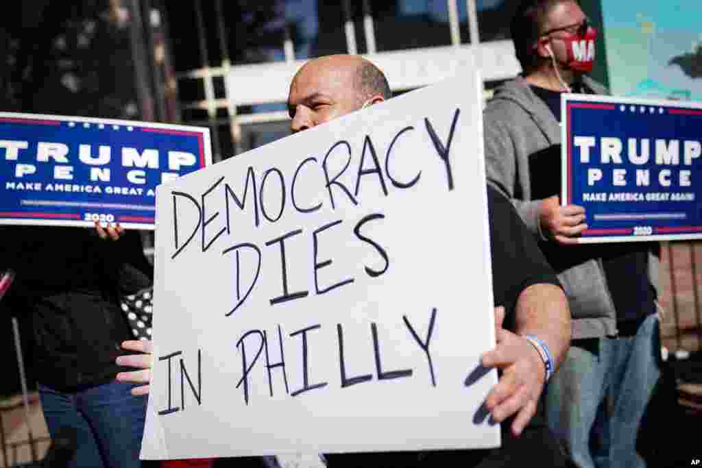 A demonstrator stands with supporters of President Donald Trump outside the Pennsylvania Convention Center where votes are being counted, in Philadelphia, Pensylvania, Nov. 6, 2020.