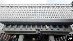 FILE - People walk in front of the Formosa Plastics Group headquarters in Taipei, Taiwan, Nov. 29, 2021. A senior executive from the company has been banned from leaving China.