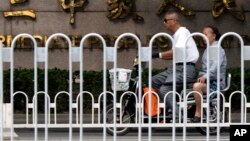 A man and woman ride an electric bike past the Tianjin No. 2 Intermediate People's Court in northern China's Tianjin Municipality, where trials are being held for four human rights advocates charged with subversion of state power.