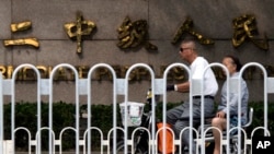 A man and woman ride an electric bike past the Tianjin No. 2 Intermediate People's Court in northern China's Tianjin Municipality, where trials are being held for four human rights advocates charged with subversion of state power.