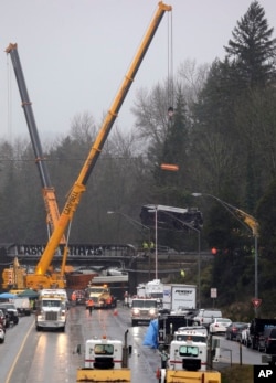 Derek digunakan untuk menurunkan gerbong kereta Amtrak yang rusak dari lintasan atas di lokasi kecelakaan maut pada Senin, di Washington, 19 Desember 2017.