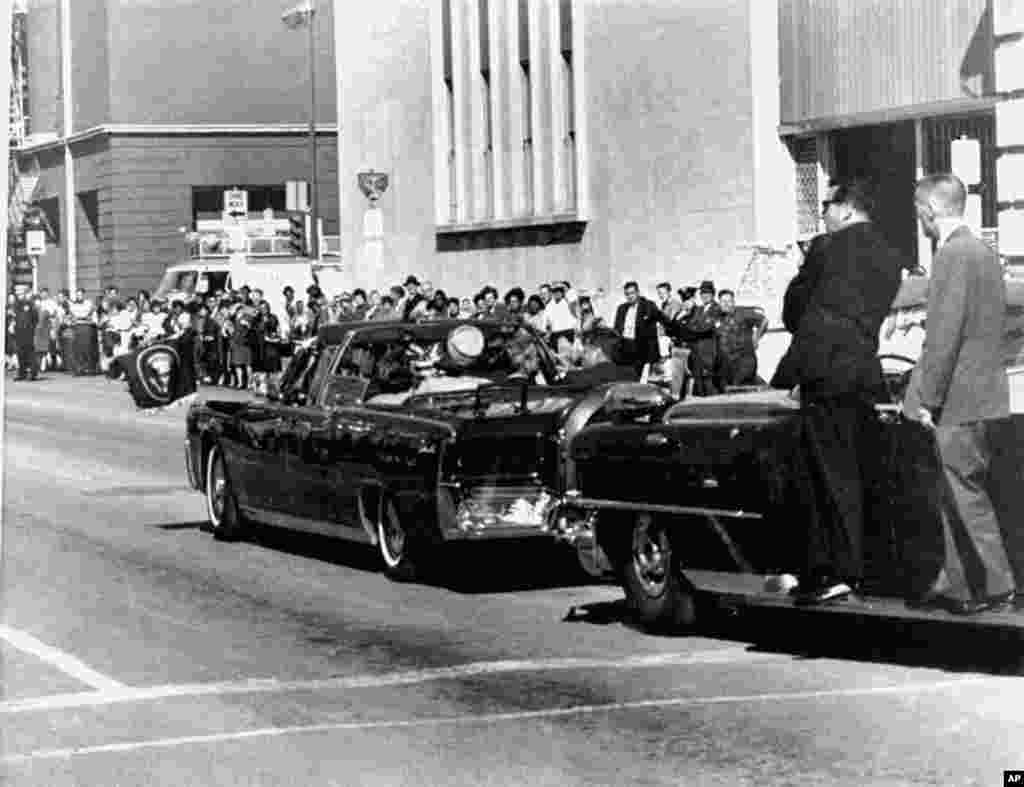 The presidential limousine carrying President John F. Kennedy and first lady Jacqueline Kennedy is followed by secret servicemen on running boards, Dallas, Texas, Nov. 22, 1963.