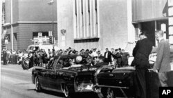 1963年11月22日肯尼迪總統訪問達拉斯時，特勤局人員在車後保護。（資料圖片）