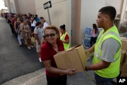 In this Dec. 21, 2017 photo, Doris Martínez receives supplies and water from municipal staff outside the City Hall in Morovis, Puerto Rico.