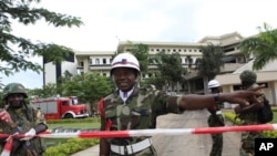 A Nigerian military policeman directs U.N. workers to another entrance, as he stands guard where a day earlier a suicide bomber crashed through an exit gate and detonated a car full of explosives in the reception area of U.N. headquarters, in Abuja, Augus