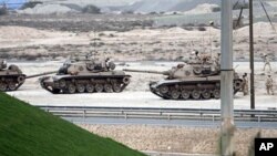 Bahraini soldiers in tanks and armored vehicles stand ready, Feb 17 2011, near a main highway west of the capital of Manama