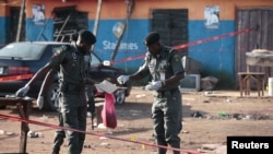 Police bomb squad personnel gather debris for analysis at the scene of a bomb blast in Nyanya, on the outskirts of Abuja, Nigeria, Oct. 3, 2015. 