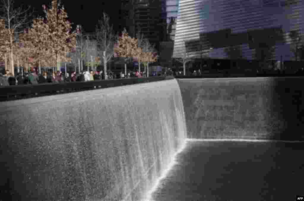 Visitors walk around the National September 11 Memorial, Thursday, Dec. 29, 2011 in New York. The memorial announced that it has had a million visitors since the site opened to the public in September. The museum entrance is at right. (AP Photo/Mark Lenni