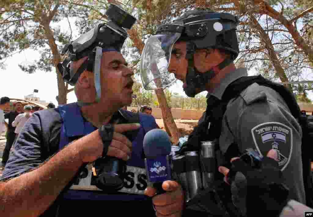 An Israeli border police confronts a journalist following clashes after the Friday prayers at the site of demolished buildings in Dar Salah, the West Bank, near Sur Baher in East Jerusalem.